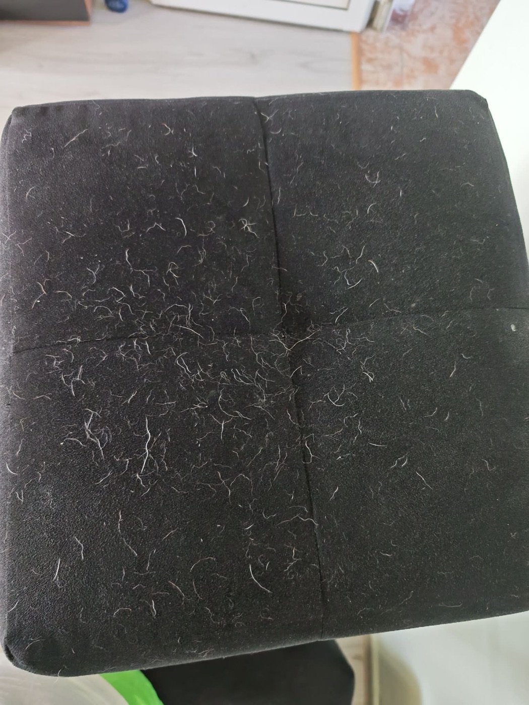 Fabric pouf covered in pet hair before cleaning